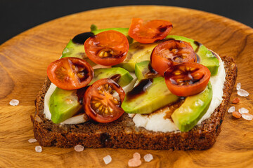 Delicious open-faced sandwich with fresh ingredients on wooden plate