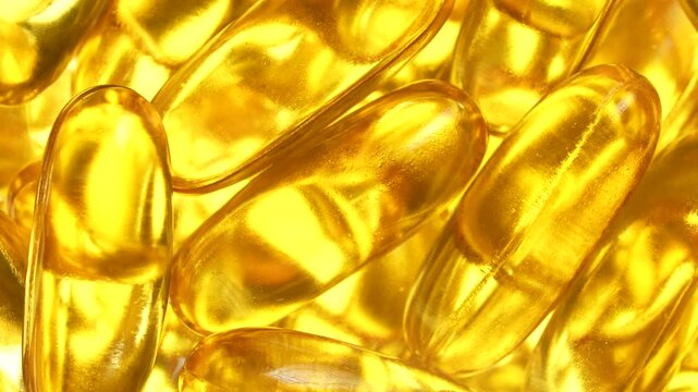 Fish oil capsules with omega 3 and vitamin D on white background, close up, rotates. Golden fish oil in gelatin capsules