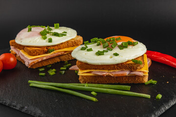 Delicious breakfast sandwiches with eggs, cheese, and ham on slate