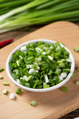 heap of green chopped onions on wooden table.
