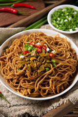 bowl with traditional hot and dry noodles on wooden table.