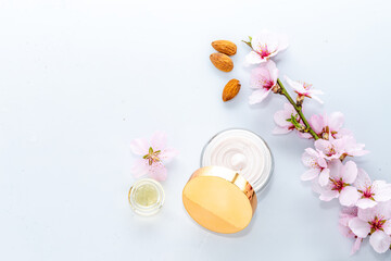 Textured Skin cream in jar, oil, reflection in lid of almond blossom on white background, cosmetic...