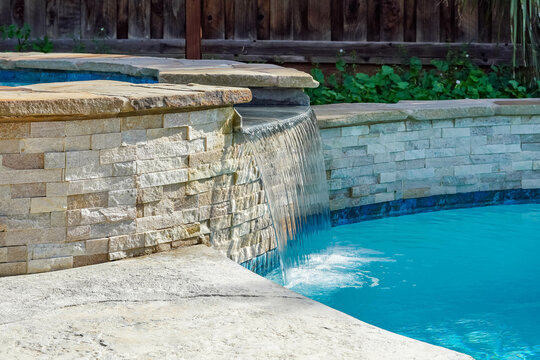 A beautiful blue pool in a backyard with water features and custom brick