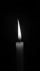 Fototapeta premium Monochrome photo with a burning candle on a black background with space for text. For themes related to remembrance, mourning, loss or spirituality, hope and keeping the fire of life burning.