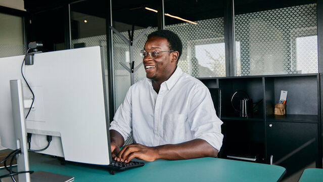 Smiling African American Business Man Working at Office Desk Using a Desktop Computer