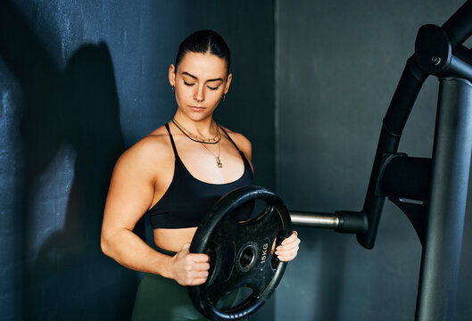Woman Preparing For Weightlifting Exercise in a Professional Gym Setting with Focused Expression