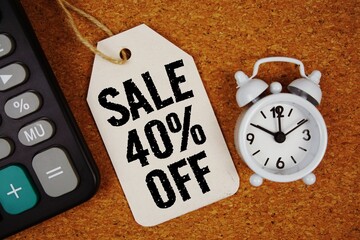 Sale 40% Off text on price tag with alarm clock and calculator on cork board background