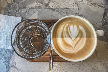A cup of latte and a glass of water on the table.
