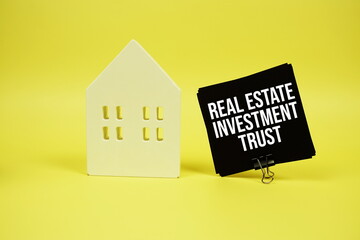 Real Estate Investment Trust text with house model on yellow background