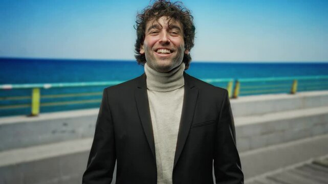 Young man smiling at the beach in front of a vibrant blue ocean offering a sense of joy and relaxation in a charming outdoor portrait that radiates positivity.