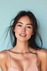 Obraz premium Beauty portrait of smiling woman with perfect skin natural makeup and glowing face in studio with blue background