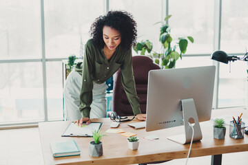 Young professional businesswoman focuses on her work in a modern, well-lit office interior beneath...