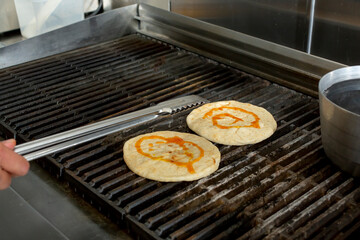 A view of a chef cooking pita bread on a restaurant grill.
