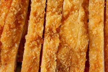 A top down view of slices of chicken katsu, as a background.