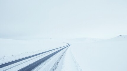 A winding road disappears into a snow covered landscape under a pale sky