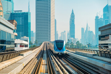 Obraz premium Dubai metro train. Fully automated and driverless train system integrated into futuristic skyline, passing through modern skyscrapers and modern architecture in Dubai city, United Arab Emirates