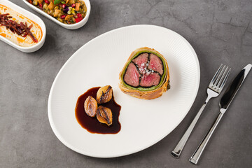 Modern plate of Beef Wellington, caramelized shallots and dark sauce
