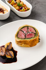Modern plate of Beef Wellington, caramelized shallots and dark sauce