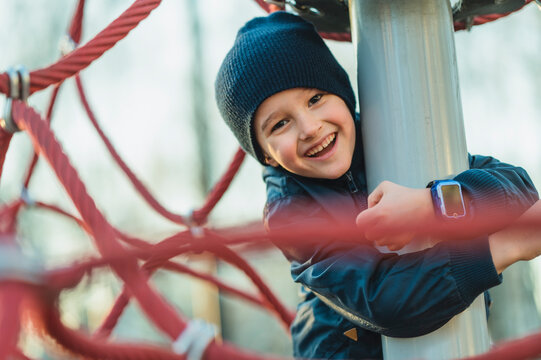 Smiling boy playing on a rope structure at the playground
