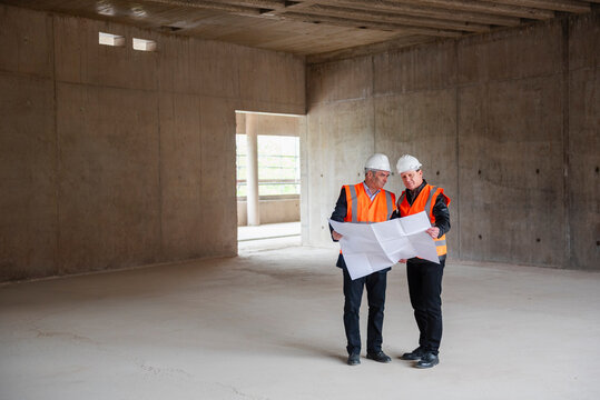 Engineers inspecting blueprints at a construction site indoors