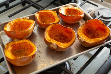 A view of baked honeynut squash halves on a baking tray.
