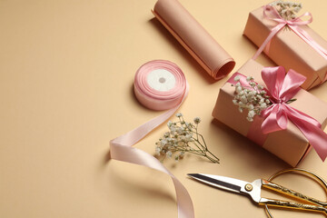 Florist. Boxes, flowers, ribbon and scissors on beige background, space for text