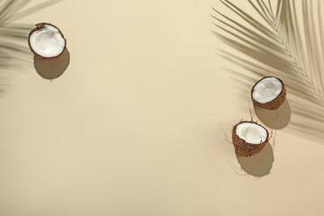 Fresh coconuts and shadow cast by tropical palm on beige background, flat lay. Space for text