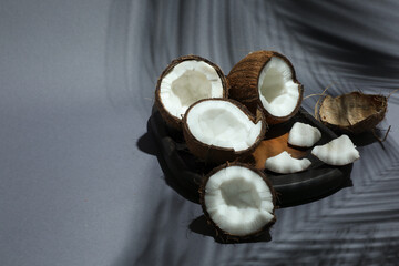 Fresh coconuts and shadow cast by tropical palm on grey background, closeup. Space for text