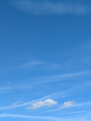 Blue Skies with wispy chemtrail aeroplane lines and fluffy white clouds