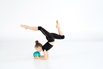 Portrait of junior gymnast in black sport swimsuit doing gymnastics exercises isolated over white...