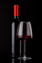 Elegant presentation of red wine in a glass and a bottle against a dark background