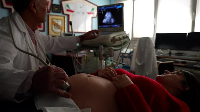 Gynecologist locating baby with ultrasound machine. Close-up on belly, 4K