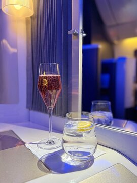 Glass of rose champagne and a glass of sparkling water in a first class cabin on an aircraft