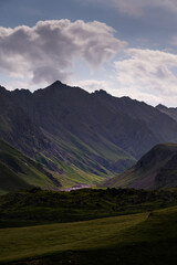Summer landscape of high mountain wall. Mountain range with cloudy sky