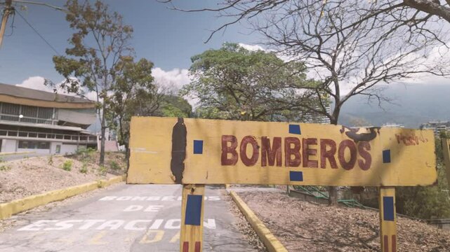 Yellow sign with word "BOMBEROS" (Firefighters). Urban setting with la cachucha background, UCV Fire Department Venezuela