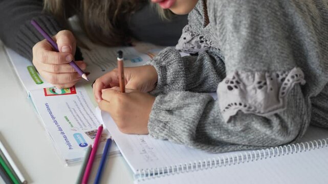 Caucasian mother and African American daughter studying at home, doing homework in cosy white room. Parent teach, child school girl learn knowledge, write exercise read book. Education for children