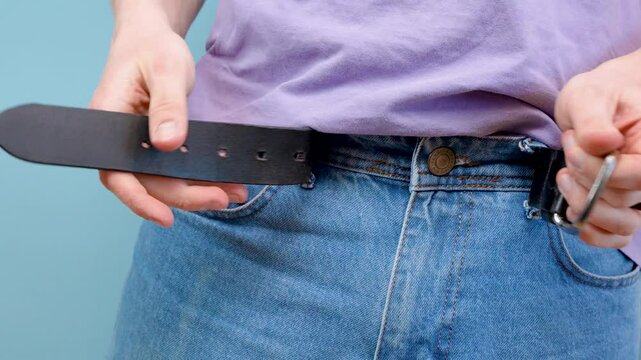 The man unbuckles the belt on his jeans