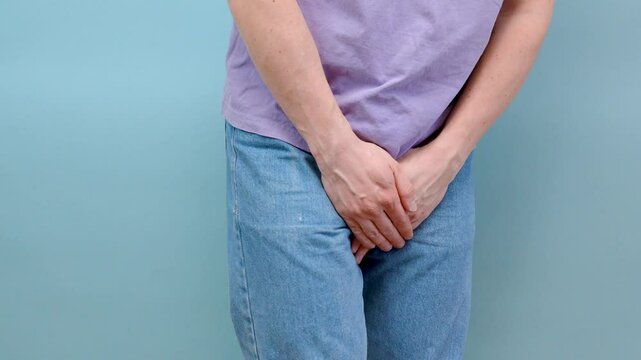 Man hold hand in front of private parts feeling discomfort from disease and inflammation. Venereal, testicular cancer. bladder problems, erectile dysfunction, premature ejaculation, prostate cancer
