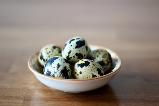 Close-up of a bowl of quail eggs on a wooden table