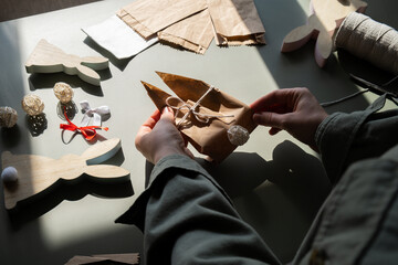 Fototapeta premium Step by step instruction of making handmade Easter gift bag rabbit bunny shaped sustainable materials decorations from craft paper. Female hands creating craft homemade present. Easter celebration