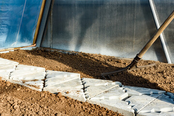 Gardener leveling soil with rake for spring planting of vegetables.