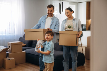 Boy is holding package with fish. Family of husband, wife and son are moving into new house