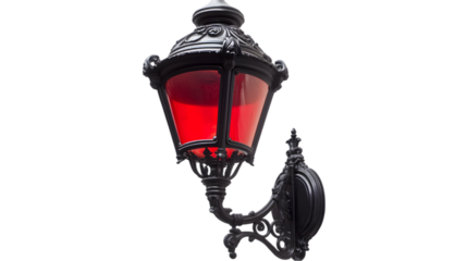Close up of an ornate black metal lamp with a red glass shade against a dark background