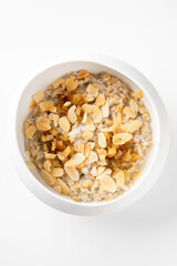 A white bowl filled with oatmeal topped with sliced almonds and dried fruit, showcasing a healthy breakfast option on a light background.
