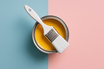 Color Palette of Creativity: An artistic perspective, a paint brush lies across a can filled with vibrant yellow paint, set against a divided backdrop of soft blue and pink.