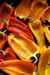 Grilled colorful peppers on a black background, focus on the middle