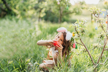 Cute funny girl with Easter eggs and bunny ears at garden. easter concept. Laughing child at Easter egg hunt. Child in park with basket full of eggs, spring concept