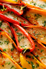 Grilled colorful pepper halves stuffed mozzarella cheese sprinkled fresh herbs, focus on the middle, close-up