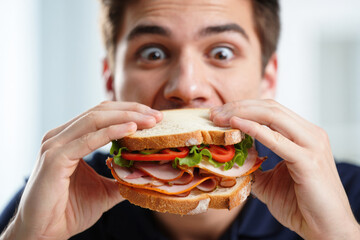 Young caucasian male enjoying a delicious sandwich with ham and vegetables