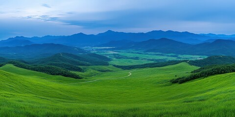 Fototapeta premium Rolling green hills and winding valley river under blue sky. Wide panoramic landscape with distant mountains. Calm optimism and renewal. Ideal for travel marketing, sustainability